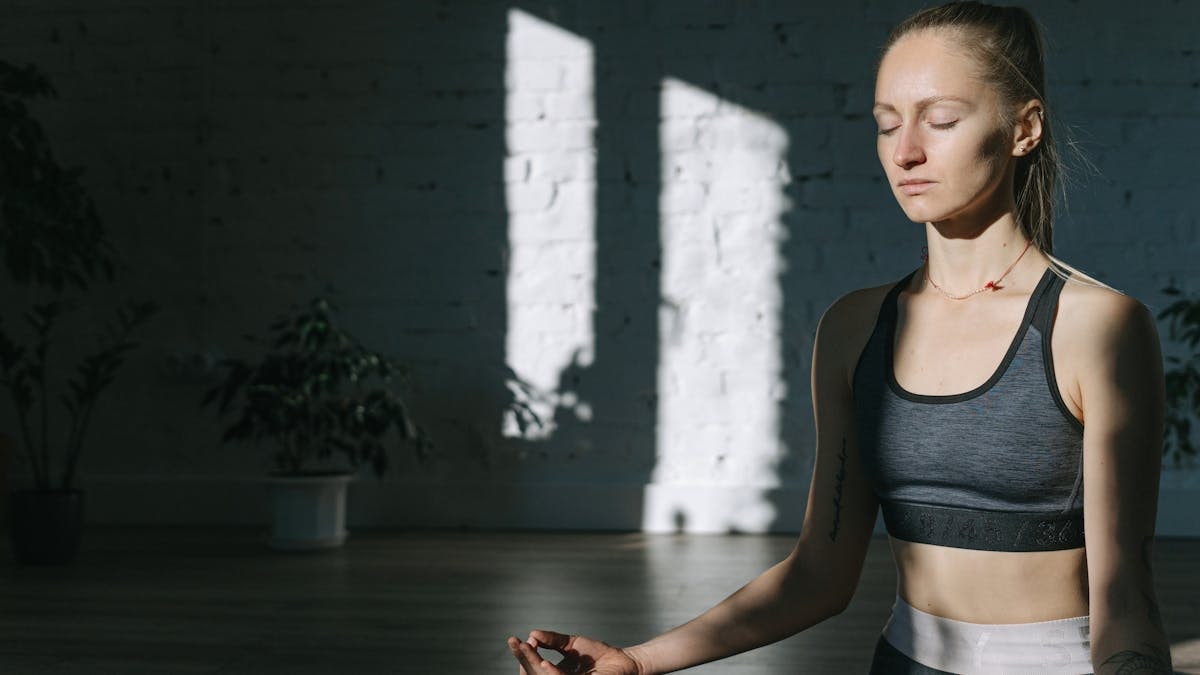 A woman meditates indoors in a serene yoga session, embracing mindfulness and tranquility.